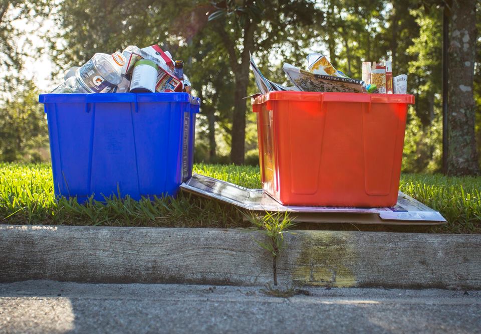 Orange and Blue Recycling Bins filled with recycling and placed on the curb